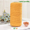 A spool of medium-thick, hand-woven, golden yellow cotton yarn for crafting, with a single rose visible nearby.