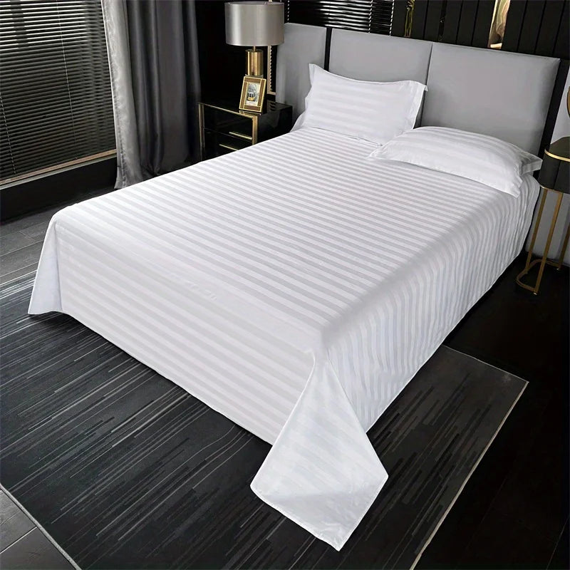 White luxury striped cotton flat sheet bedding on a bed with gray linens and dark wood accents.