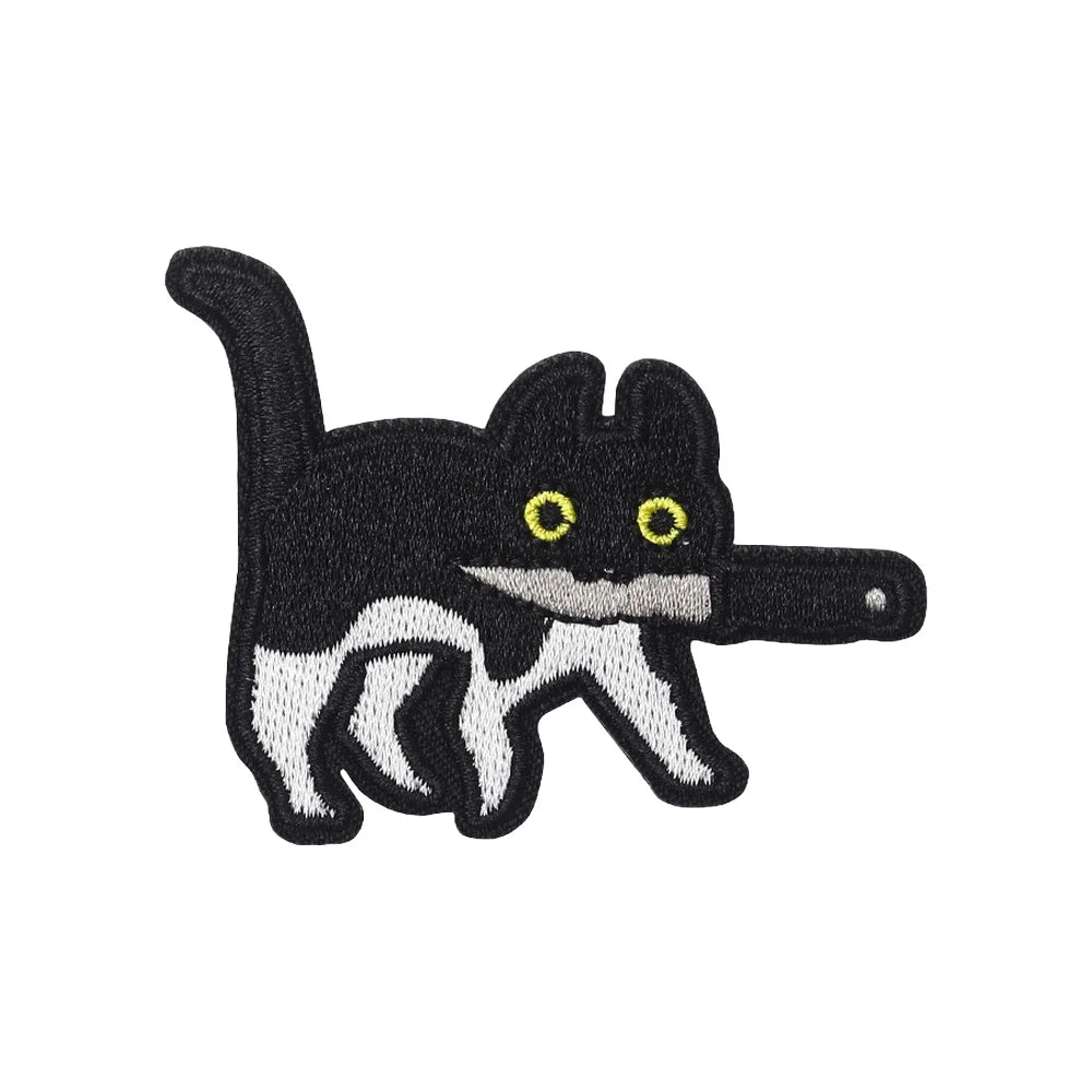 A black and white embroidered patch of a cat with yellow eyes, resembling an assassin.