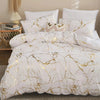 White duvet cover set with gold marble print and accent pillows on a bed.