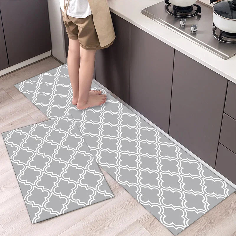 Two gray and white diamond print non-slip kitchen rugs placed on a light wood floor.