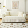 A cream-colored Jacquard elastic sofa cover with a pleated skirt displayed in a bright, modern living room.