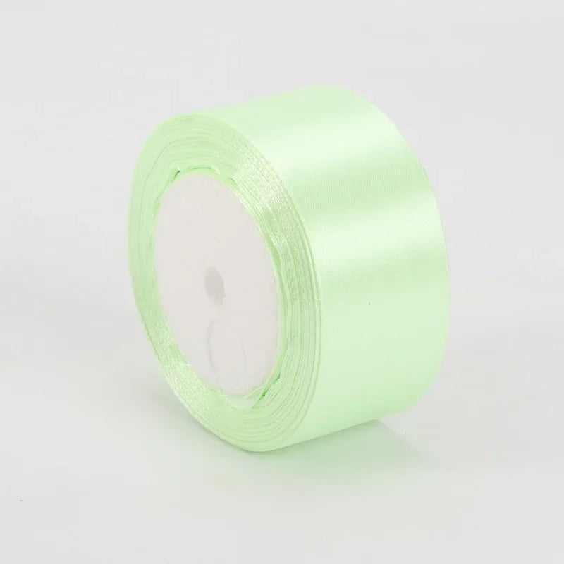 A roll of light green satin ribbon used for crafts and gift wrapping.