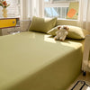 A bright yellow-green organic cotton bedding set with a light green sheet, pillows, and a teddy bear on a bed.