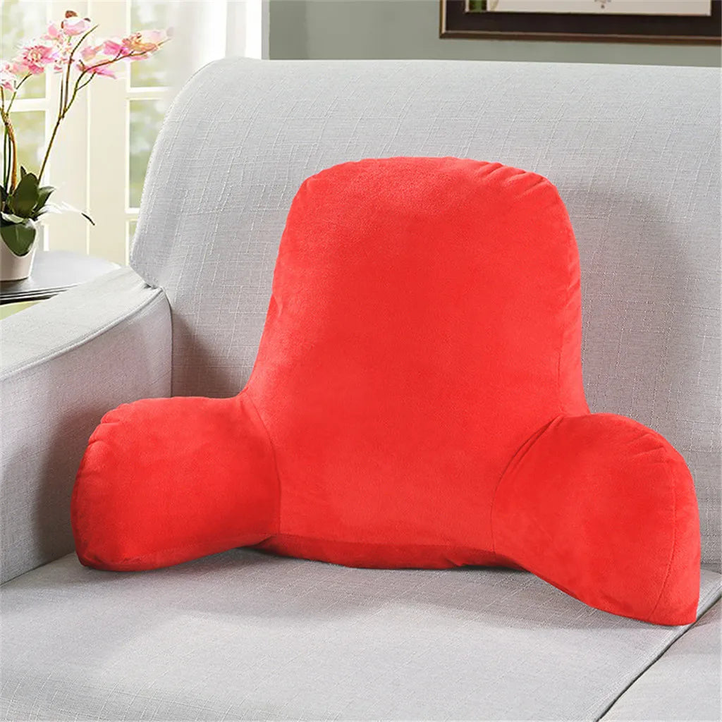 A bright red plush lumbar support cushion with arms resting on a light gray sofa.