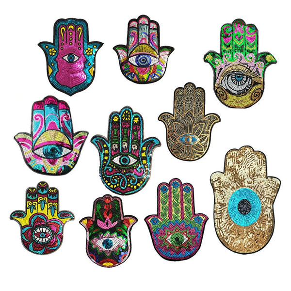 A collection of ten colorful handprint designs featuring various eye motifs and patterns made with sequins.
