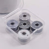 A clear plastic container holds several spools of prewound sewing machine bobbin threads.