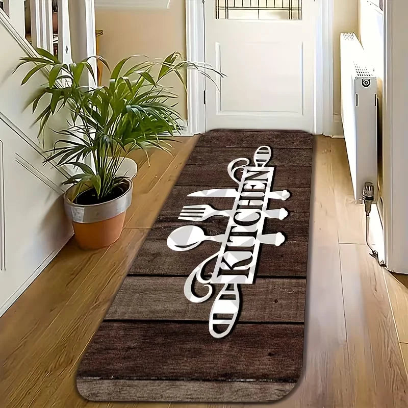 A dark brown floor mat with white silhouette text spelling out KITCHEN is placed on a light wooden floor.