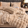 A beige plush rabbit hair bedding set featuring a fluffy duvet and pillows on a bed.