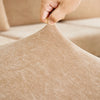 A hand is pulling a beige stretchable chenille sofa cushion cover fabric taut.