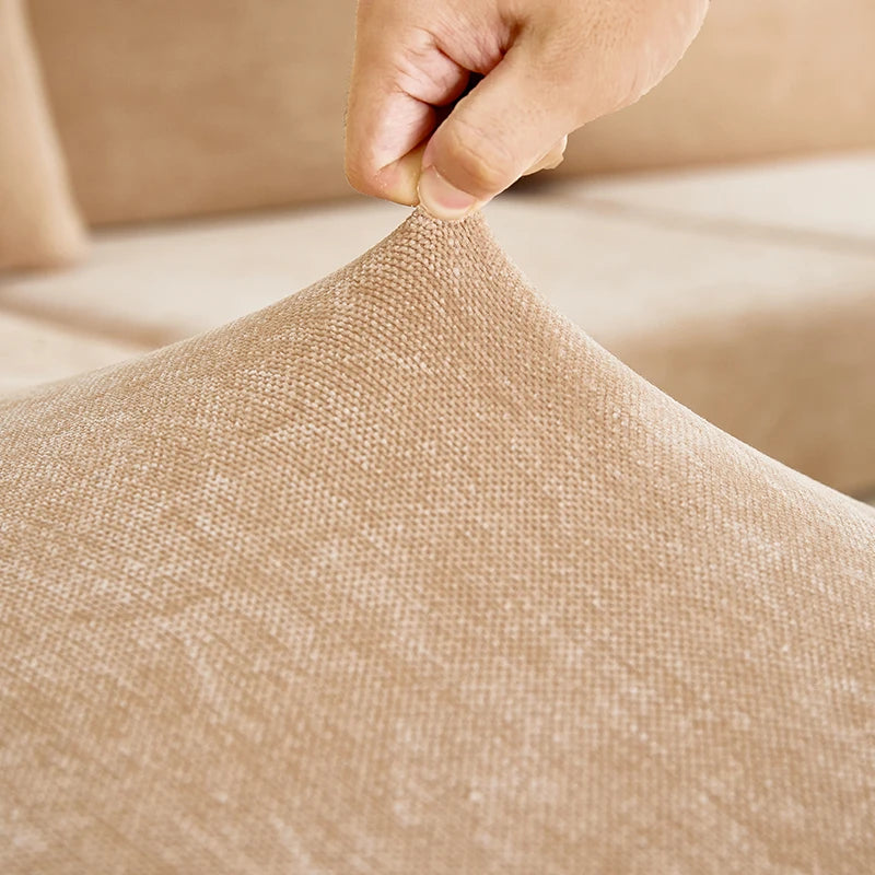 A hand is pulling a beige stretchable chenille sofa cushion cover fabric taut.