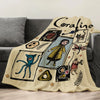 A cream colored flannel throw blanket featuring a graphic design of a cat and various illustrated elements.