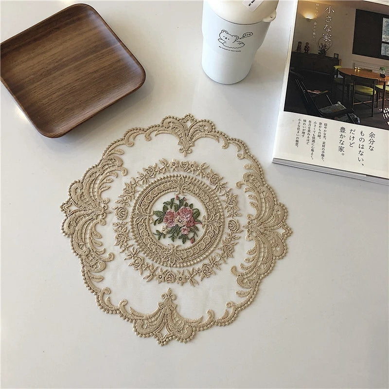 An elegant oval lace embroidered coaster set with delicate floral patterns on a white background.