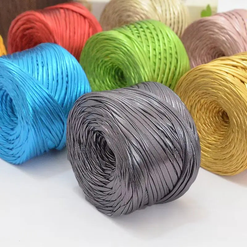 A collection of various colored metallic cake yarn spools arranged on a white surface.