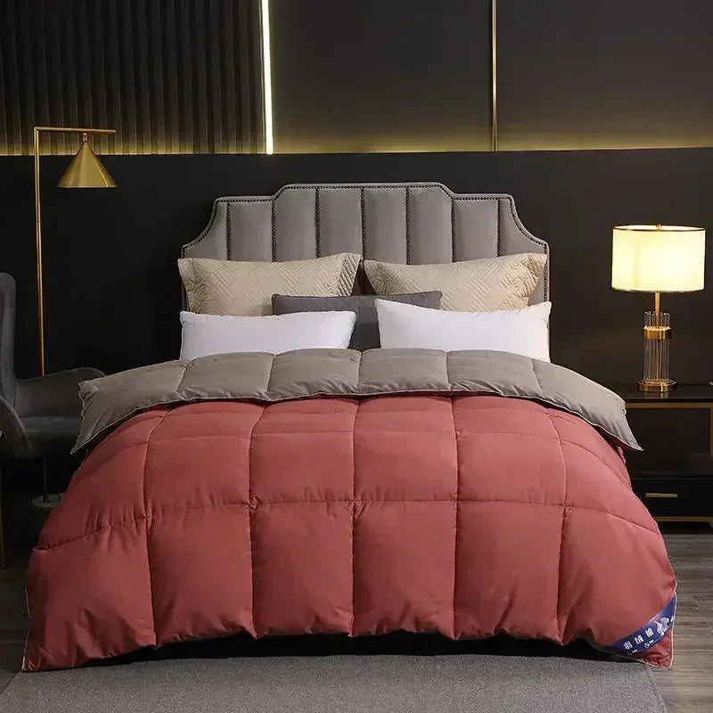 A pink quilted comforter duvet with a gray cover and white pillows displayed on a bed against a dark wall.
