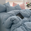 A light blue duvet cover set with matching pillows and a black book resting on the bedding.