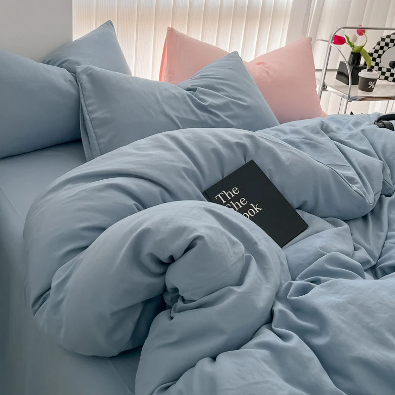 A light blue duvet cover set with matching pillows and a black book resting on the bedding.
