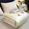 A cream-colored embroidered cooling summer quilt folded neatly on a white surface.