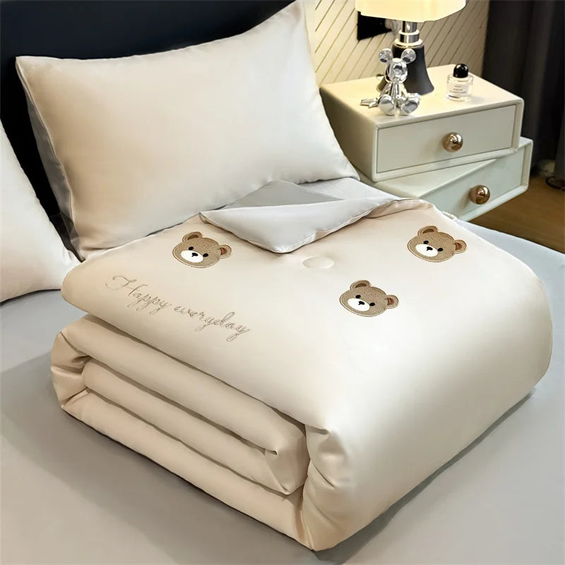 A cream-colored embroidered cooling summer quilt folded neatly on a white surface.