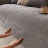 A hand touches a textured gray chenille sofa cushion cover on a sofa.