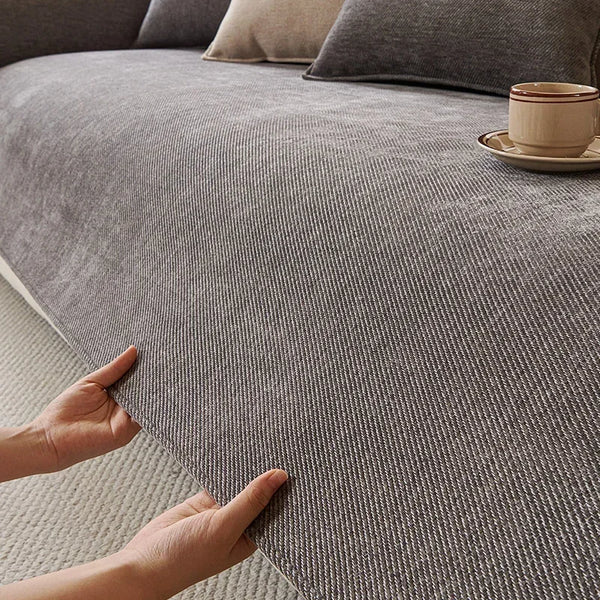 A hand touches a textured gray chenille sofa cushion cover on a sofa.