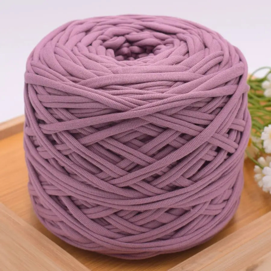 A ball of purple craft yarn for knitting and DIY displayed on a wooden surface.