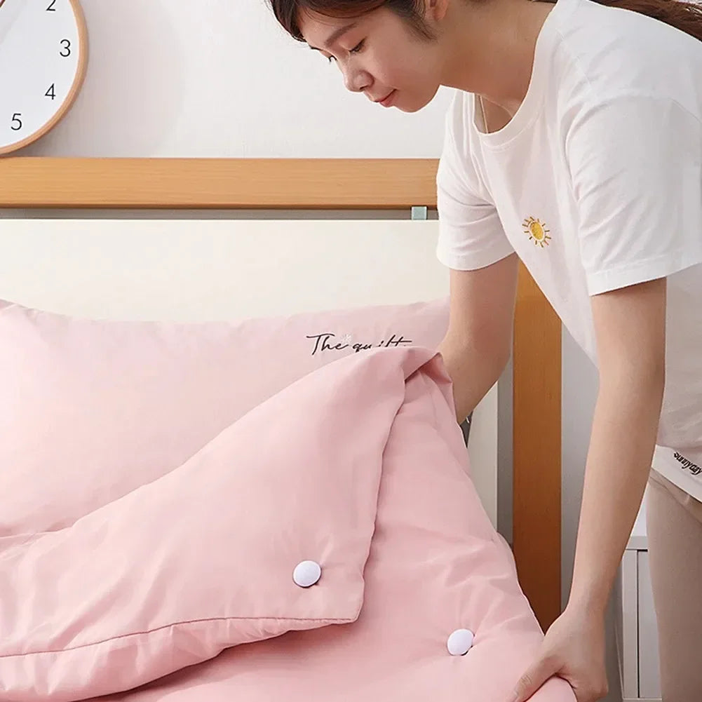 A person is adjusting a pink quilt with fabric clips in a bright room.