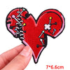 Red heart shaped embroidered patch with various colored pins and needles on a black background