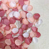 A collection of pink and blush silk rose petals in various shades are arranged on a light background.