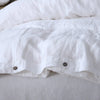 White luxury French linen duvet cover folded on a bed