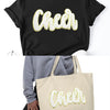 Black t-shirt with a gold glitter cheer letter design on the chest.