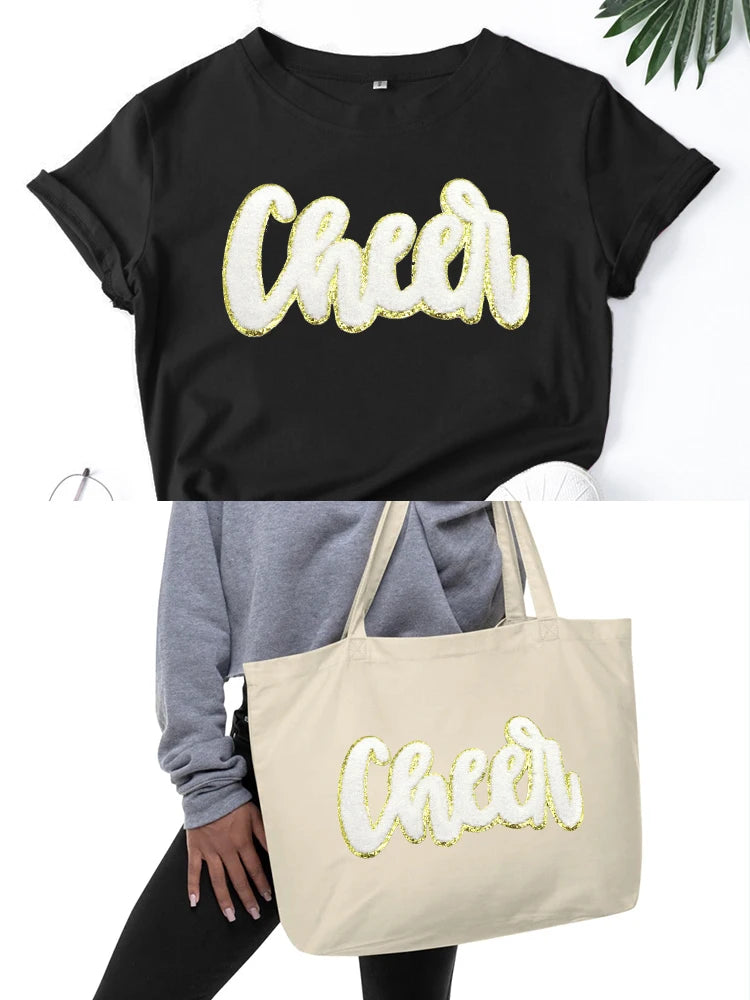 Black t-shirt with a gold glitter cheer letter design on the chest.