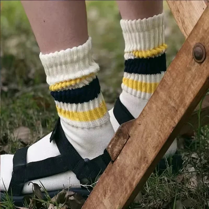 A close-up of a person's legs and feet wearing white and navy striped crew socks.