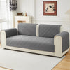 A modern sofa featuring gray geometric quilted cushion covers on a light cream frame.