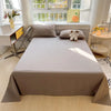 A light beige organic cotton bedding set featuring a flat sheet, pillow, and a stuffed dog toy on a bed.