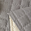 Close-up of a gray quilted anti-slip sofa cover with a plush texture and visible stitching.