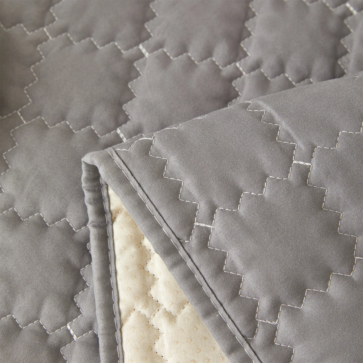 Close-up of a gray quilted anti-slip sofa cover with a plush texture and visible stitching.