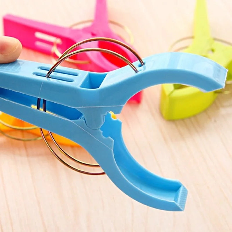 A blue plastic clothespin is shown against a light wooden background, with other colored clothespins visible in the blurred b