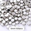 A pile of silver-colored geometric acrylic beads for jewelry making