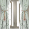 Light green sheer curtains tied back with natural fiber tassels framing a doorway.