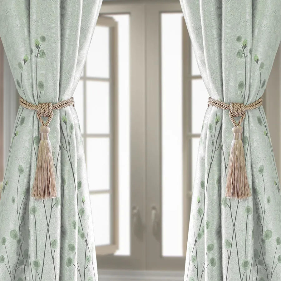 Light green sheer curtains tied back with natural fiber tassels framing a doorway.