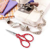 A roll of measuring tape and a pair of embroidery scissors are displayed on a white background.