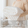 A person is holding a fluffy white throw blanket with features like ultra soft, lightweight, breathable, and machine-washable