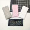 Pink and gray suede-like squeeze-top PU leather eyeglass cases with matching cleaning cloths displayed on a dark grid.