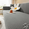 A gray jacquard sofa cover featuring white and orange decorative pillows on a modern sofa.