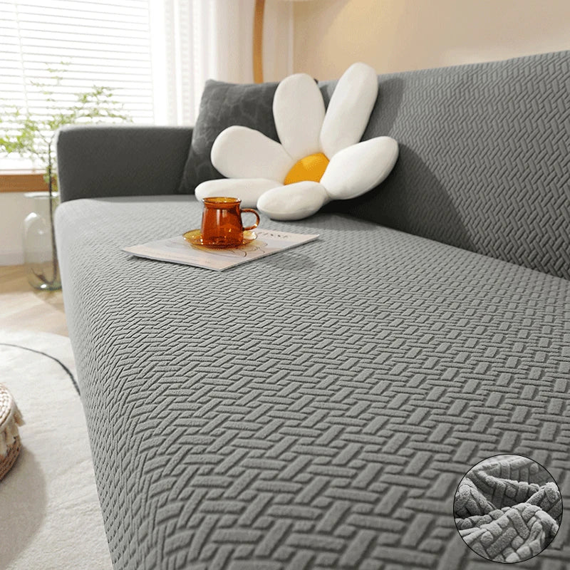 A gray jacquard sofa cover featuring white and orange decorative pillows on a modern sofa.
