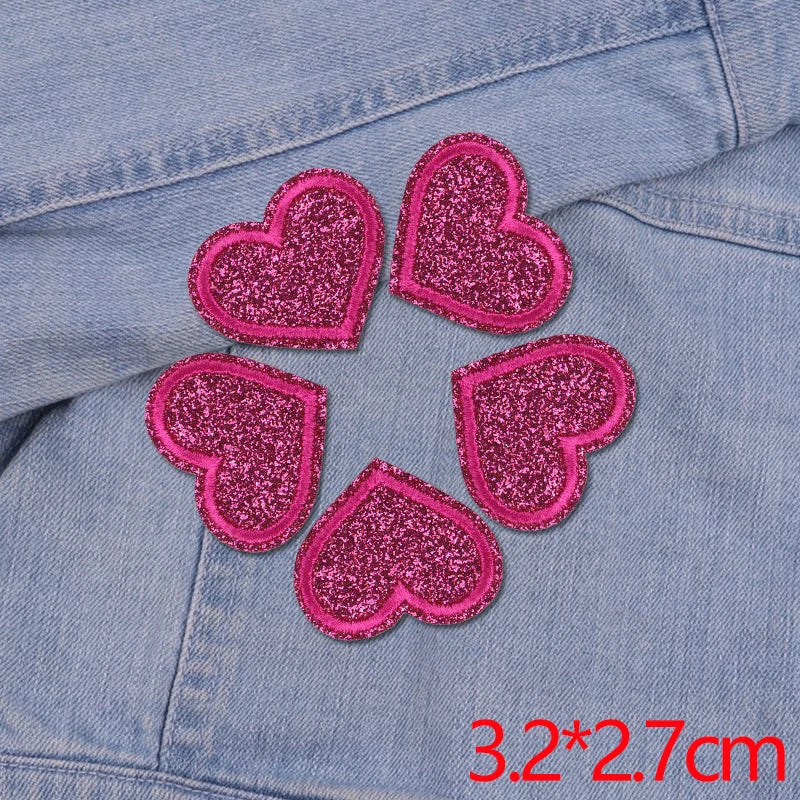 Five pink glitter heart patches arranged in a circle on a denim fabric