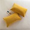 A square yellow velvet throw pillow resting on a white surface, with a small card nearby.