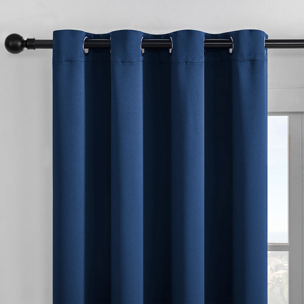 Solid blue blackout window curtain hanging from a black rod.
