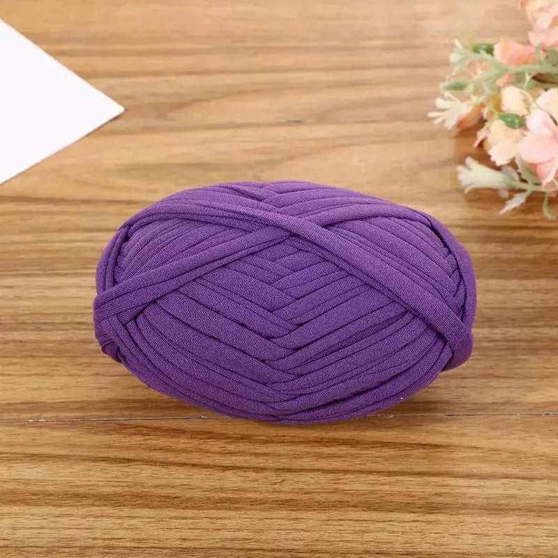 Purple flat thread yarn coiled on a wooden surface for crafting and sewing